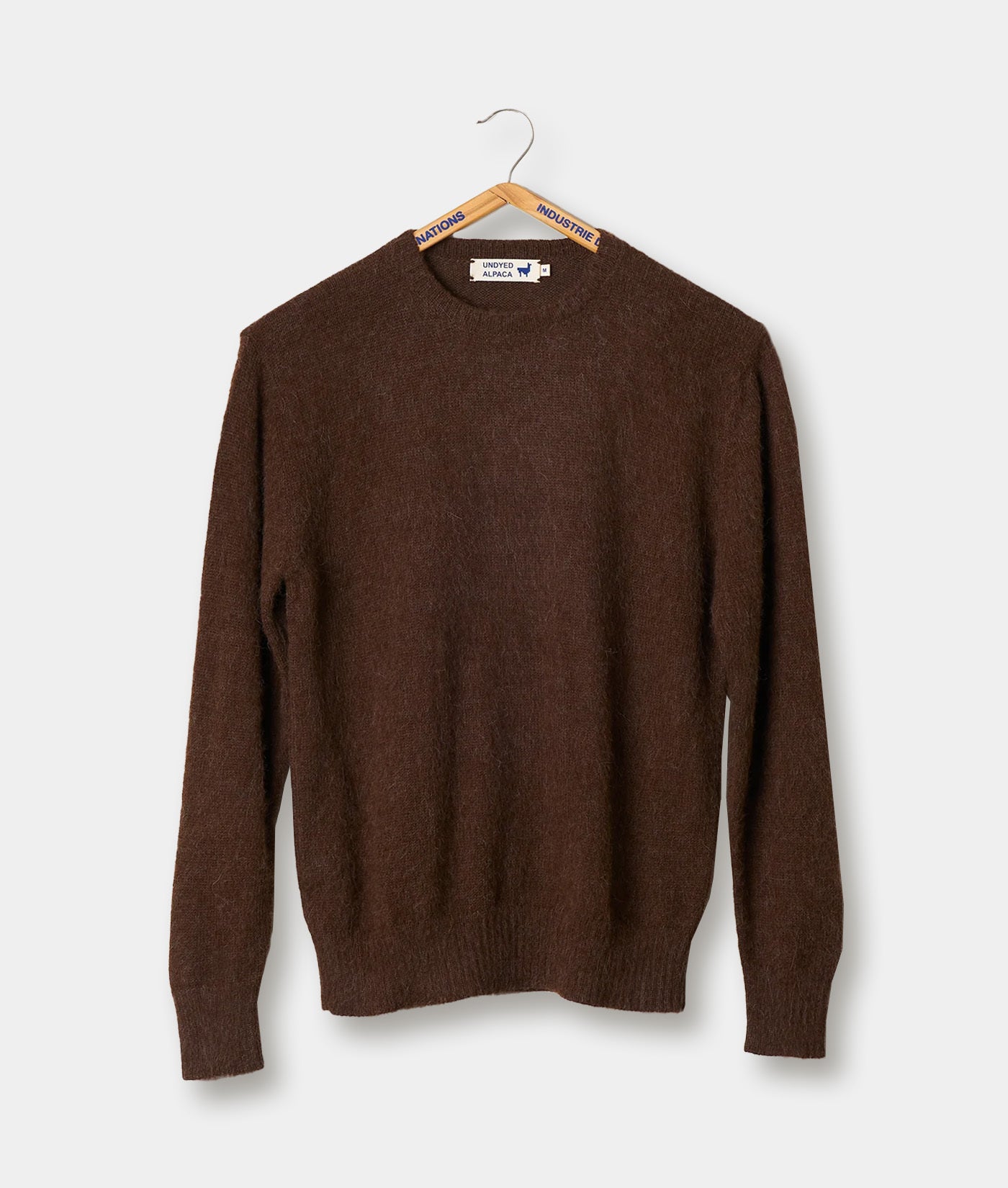 A brown alpaca fiber crewneck sweater hanging on a hanger against a white background.