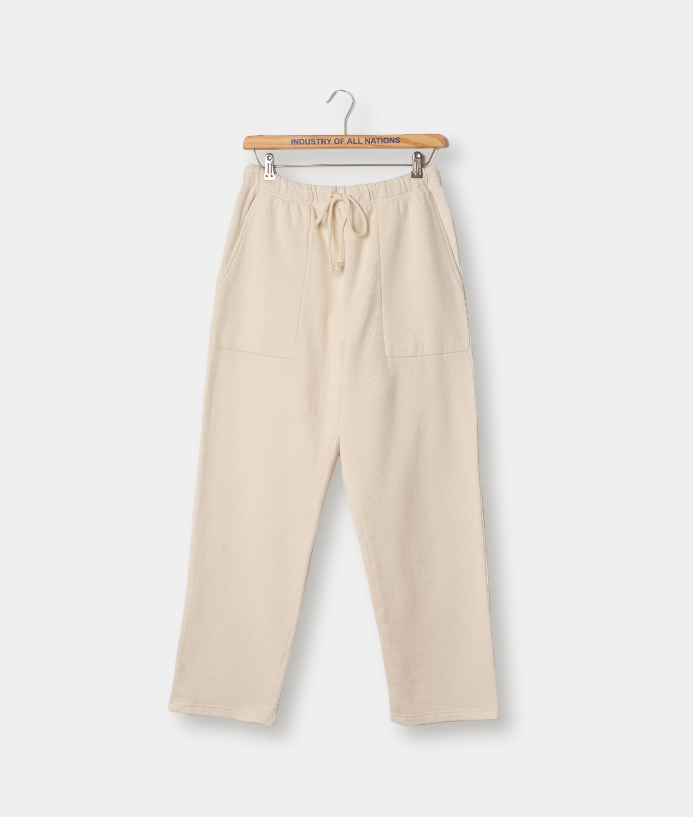 A pair of beige sweatpants with an elastic waistband, hanging on a hanger against a white background.
