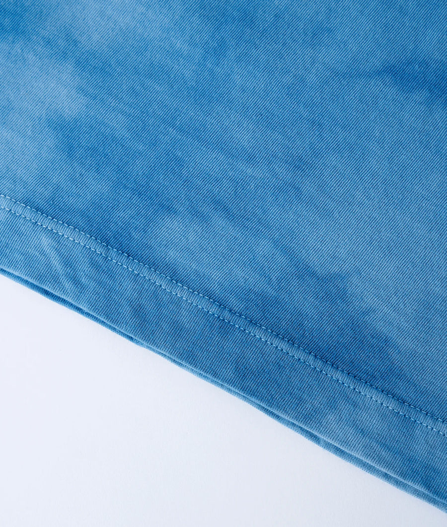 Close-up detail shot of a blue denim fabric with visible stitching and seams - Industry of All Nations