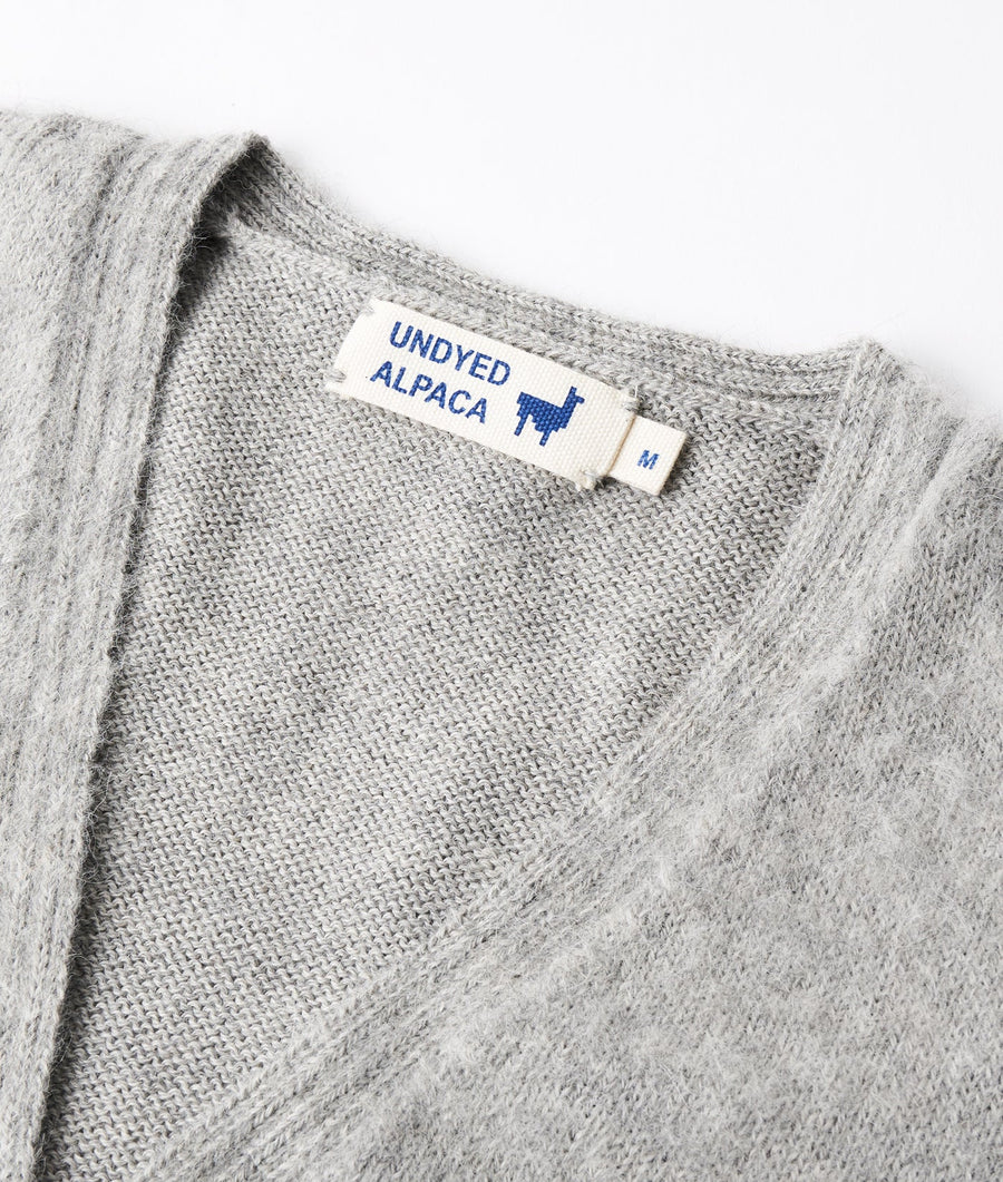 Gray alpaca sweater with "Undyed Alpaca" label displayed on close-up shot of folded garment - Industry of All Nations