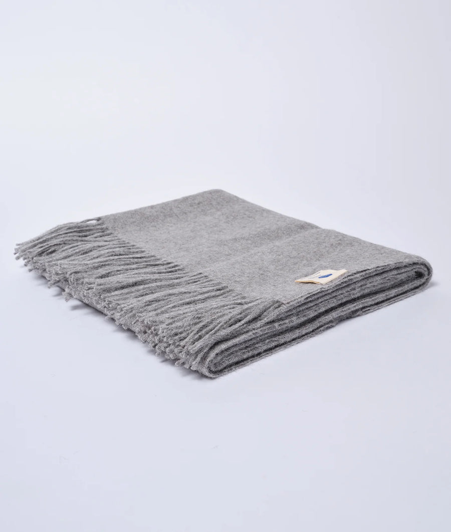 A folded, grey wool blanket with tasseled edges, displayed flat on a white background - Industry of All Nations
