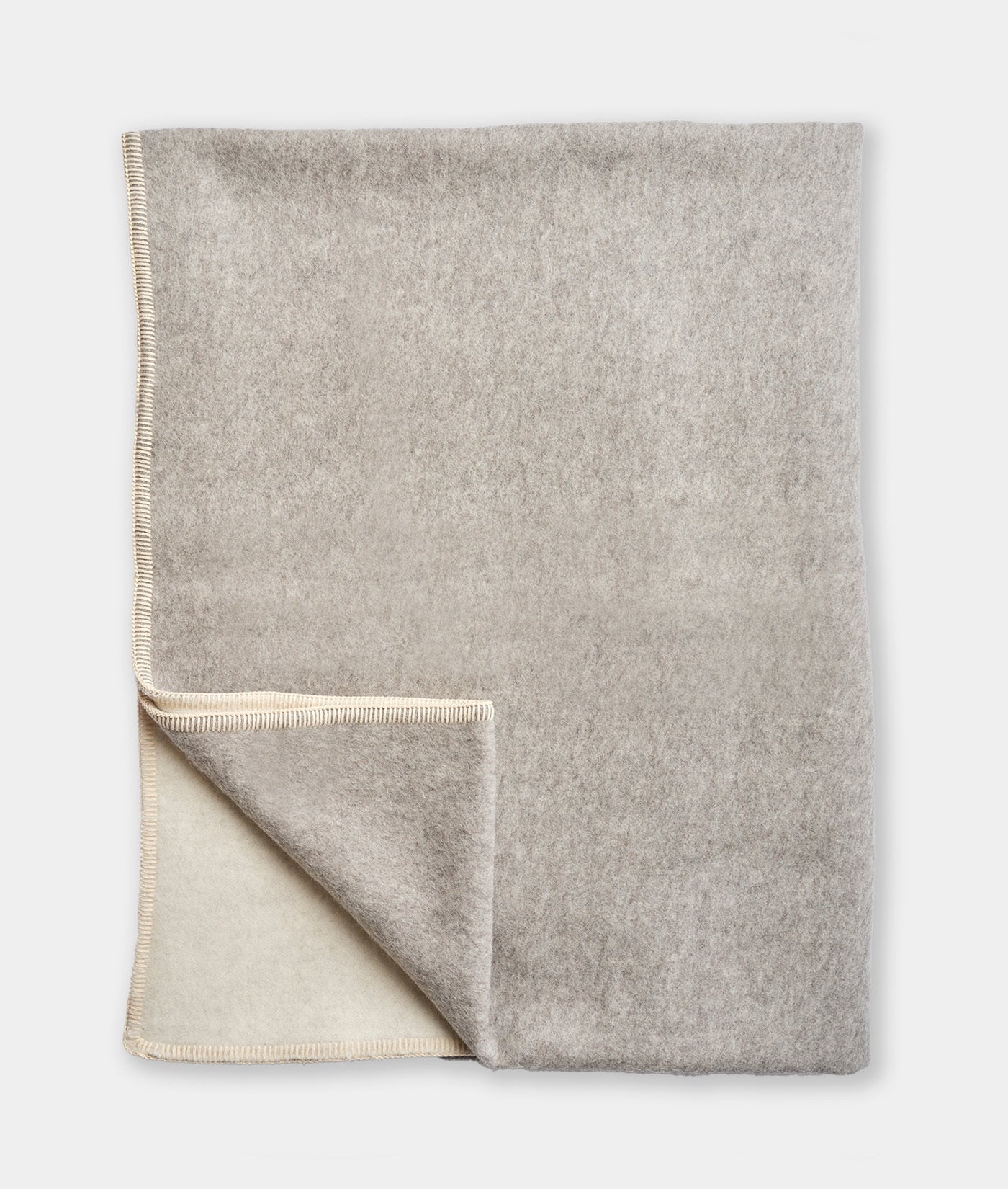 Folded gray blanket with a white interior on a light gray background