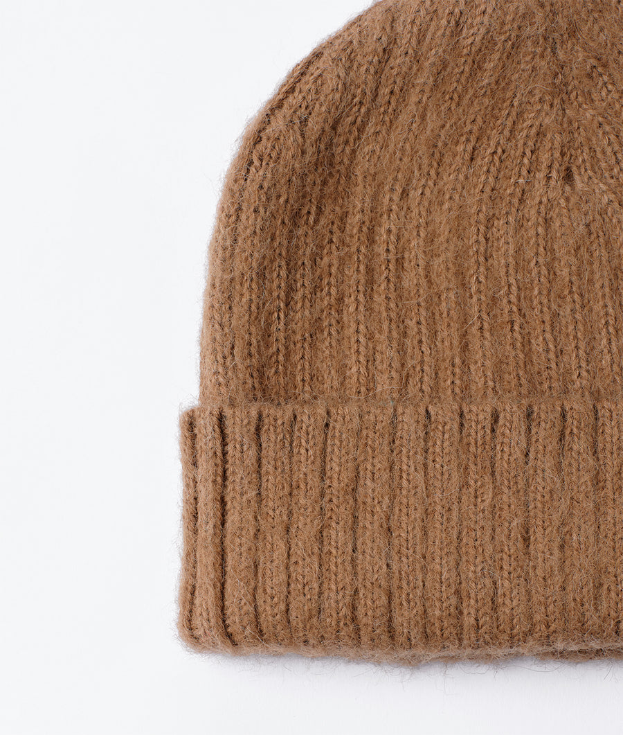 A close-up detail shot of a light brown, knit wool hat against a plain white background - Industry of All Nations