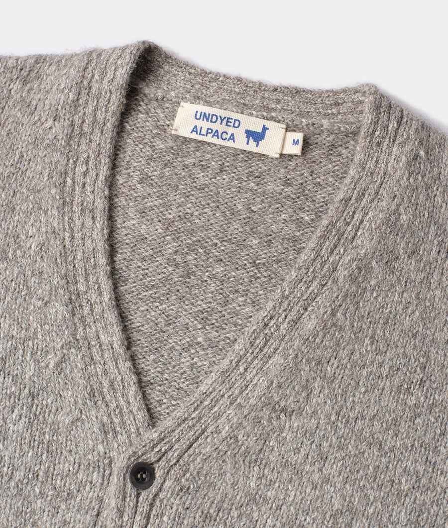 A close-up detail shot of a gray knitted alpaca cardigan with an "Undyed Alpaca" label - Industry of All Nations