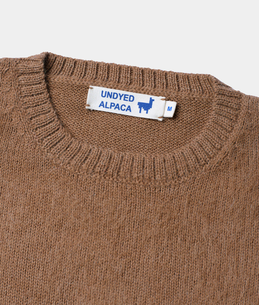 A close-up detail shot of a brown alpaca knitted sweater with a sewn-in "UNDYED ALPACA" label - Industry of All Nations