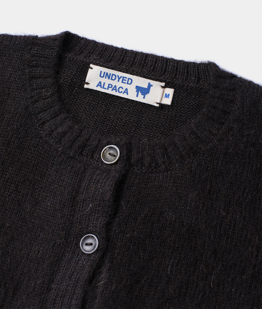 Close-up shot of a black knit Undyed Alpaca cardigan with buttons and brand label - Industry of All Nations