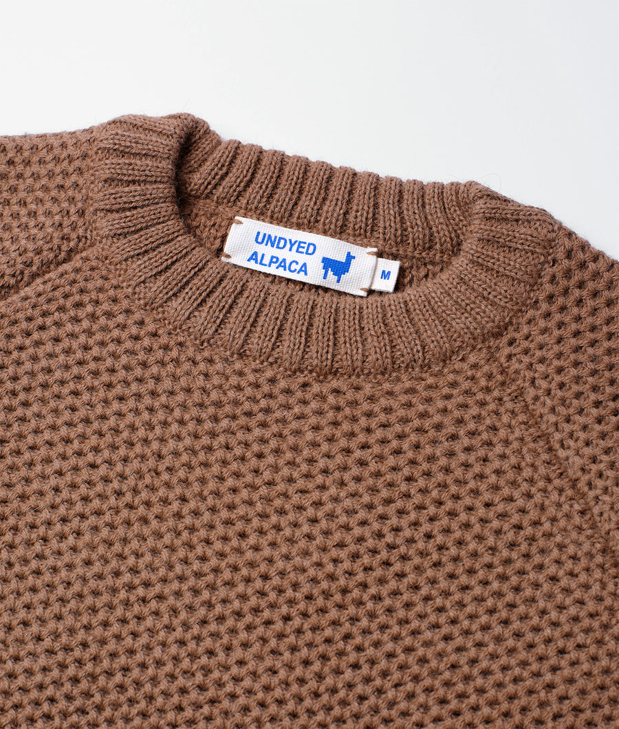 Knitted brown alpaca sweater with Undyed Alpaca label, displayed as a close-up detail shot - Industry of All Nations