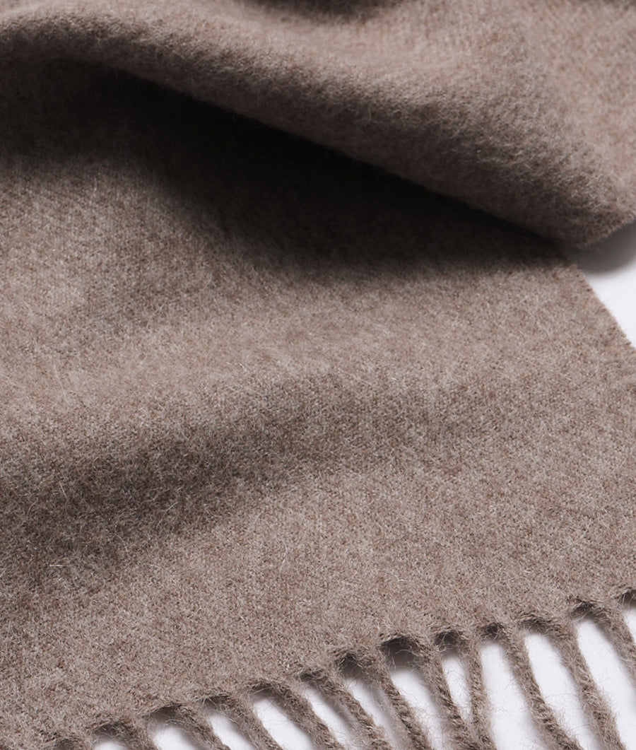 A close-up detail shot of a tan-colored, alpaca wool blanket or throw with visible fringes - Industry of All Nations