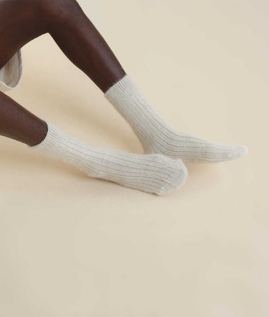 A close-up view of a pair of gray crew socks, displayed on a person's legs - Industry of All Nations