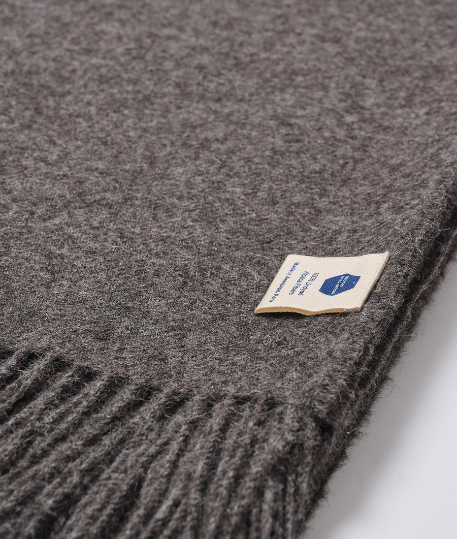 Closeup detail shot of a gray wool scarf with a woven label from Industry of All Nations.