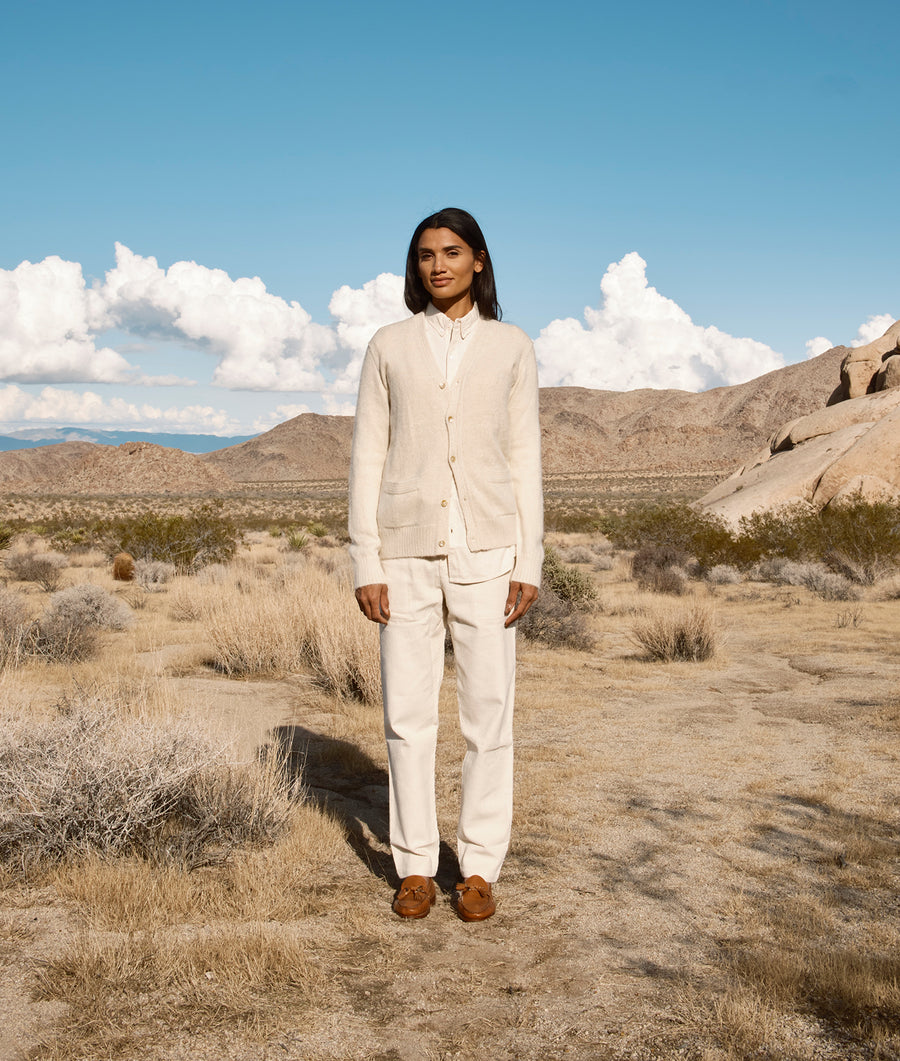 A person wearing a white cotton suit standing in a desert landscape - Industry of All Nations