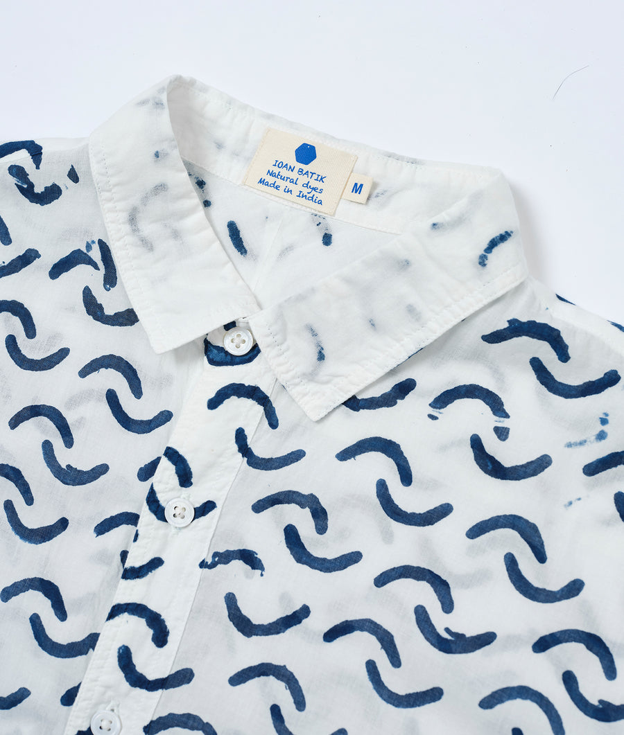 A white button-up shirt with a bold, navy blue abstract pattern, displayed in a flat lay - Industry of All Nations
