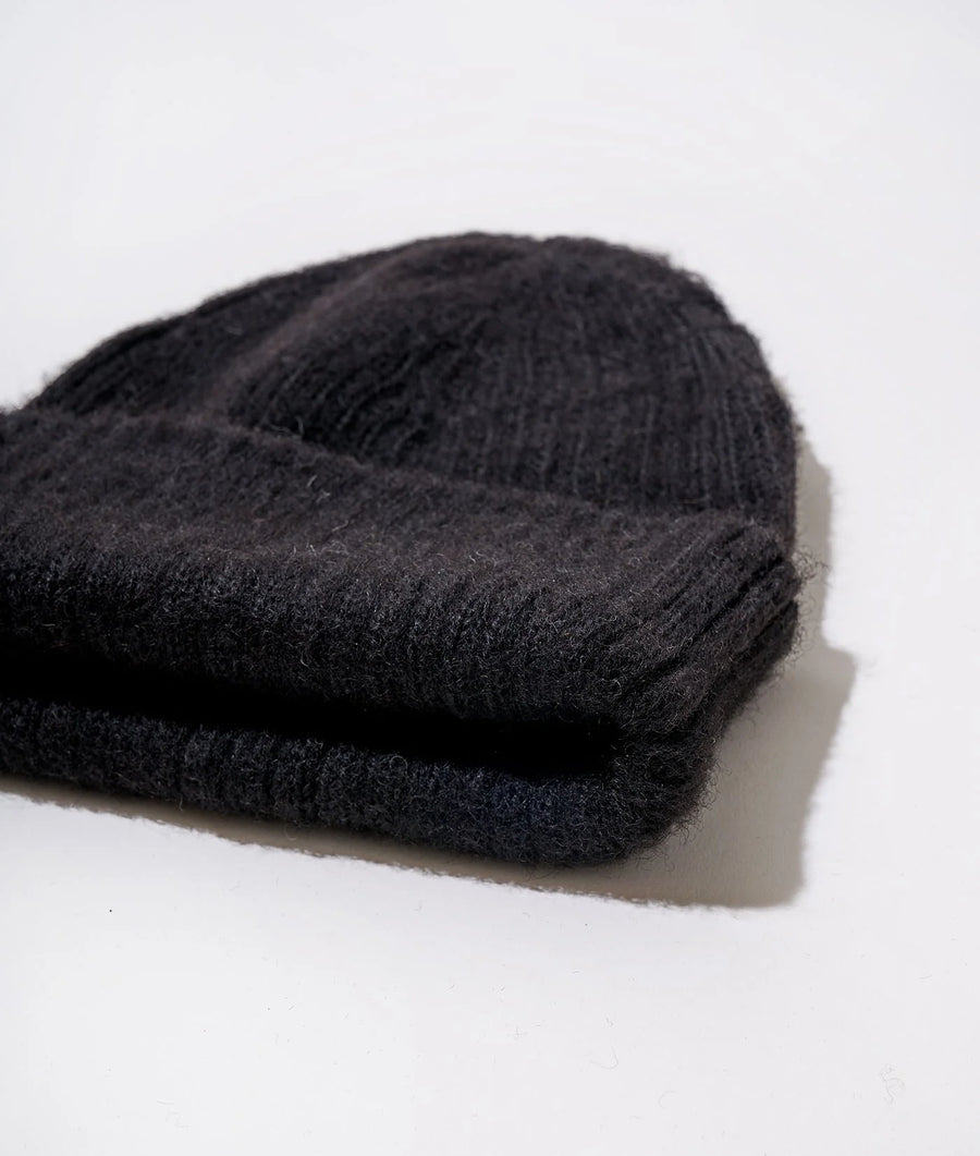 Black knit beanie cap displayed on a white surface - Industry of All Nations