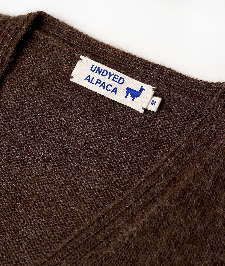 Close-up of a brown alpaca wool sweater or jumper with a label that reads "Undyed Alpaca" - Industry of All Nations