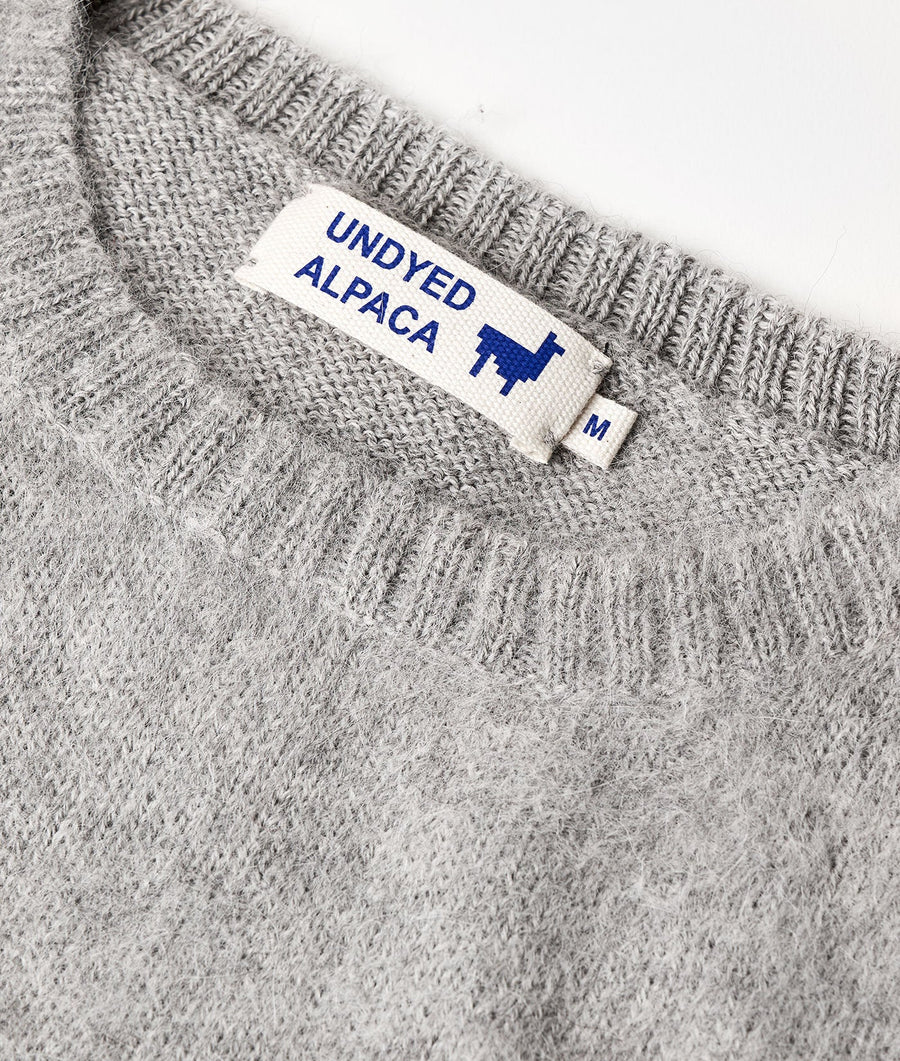 A close-up shot of a gray alpaca knit sweater with a "Undyed Alpaca" label - Industry of All Nations