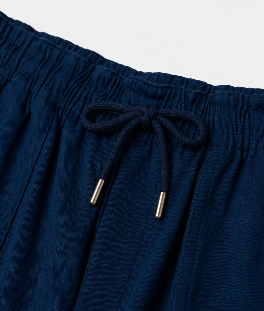 Close-up of dark navy blue drawstring shorts showing the elasticized waistband and metallic silver tips of the drawstrings.
