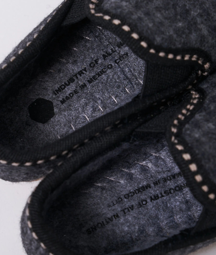 Close-up detail shot of a black, knitted garment with stitched logo tag from Industry of All Nations.