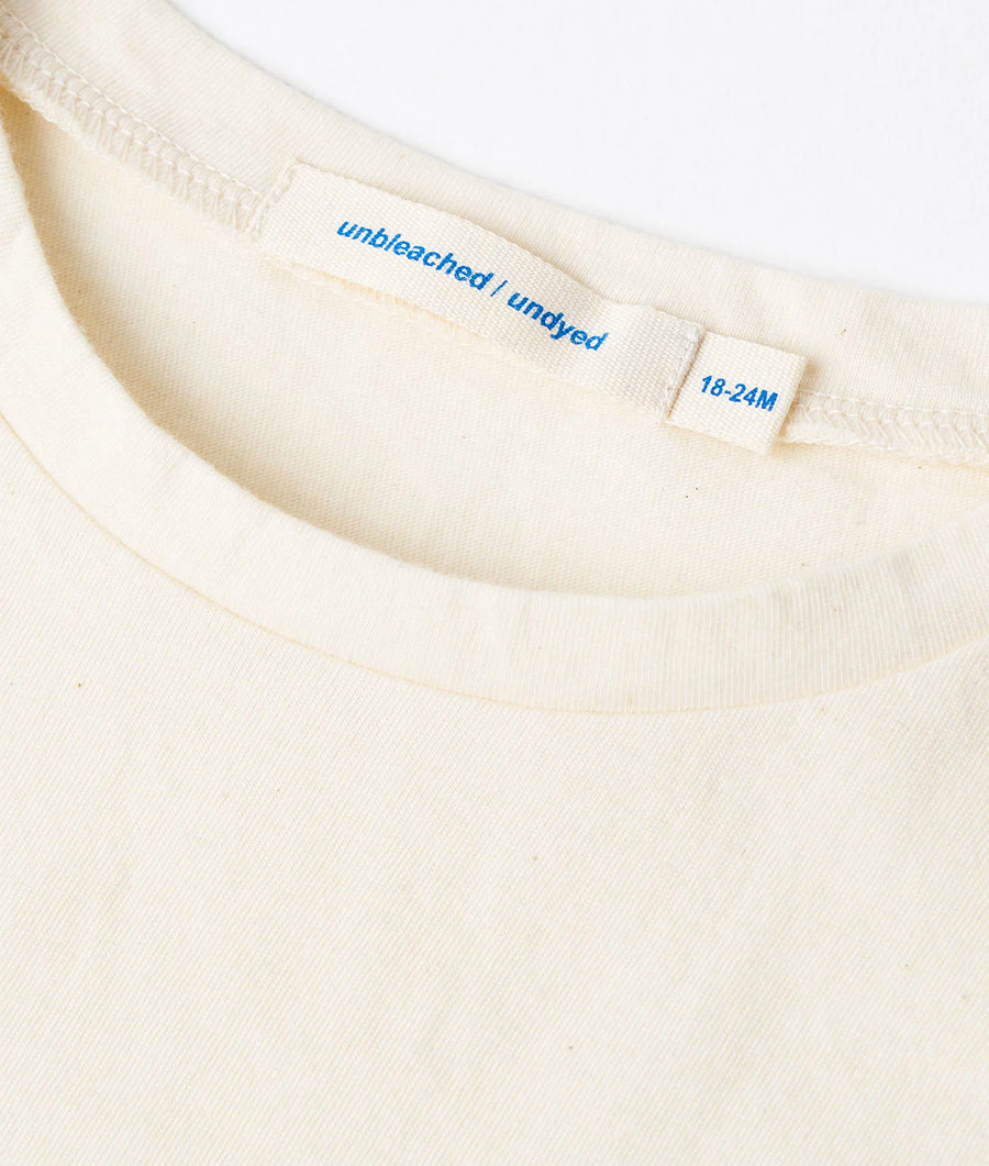 Close-up detail image of an unbleached, undyed cream-colored cotton t-shirt with a size tag - Industry of All Nations