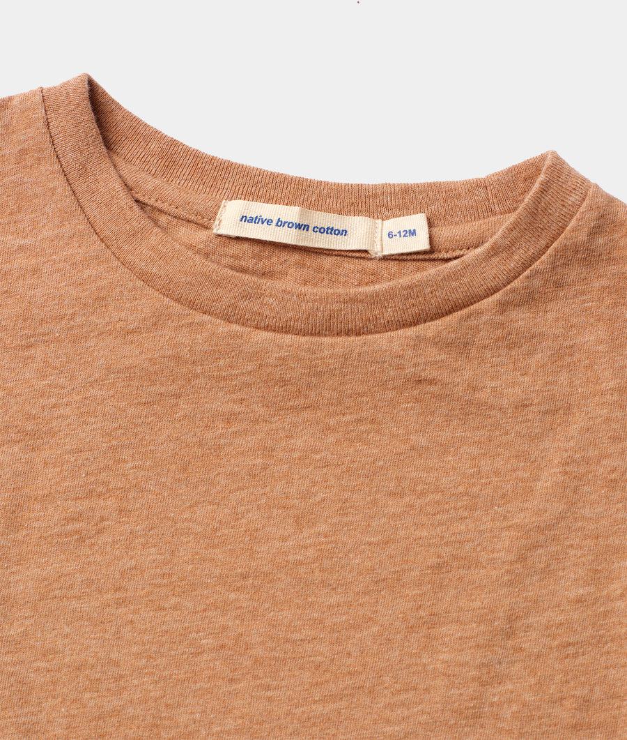 Close-up detail shot of a rust-colored native brown cotton t-shirt with size tag - Industry of All Nations