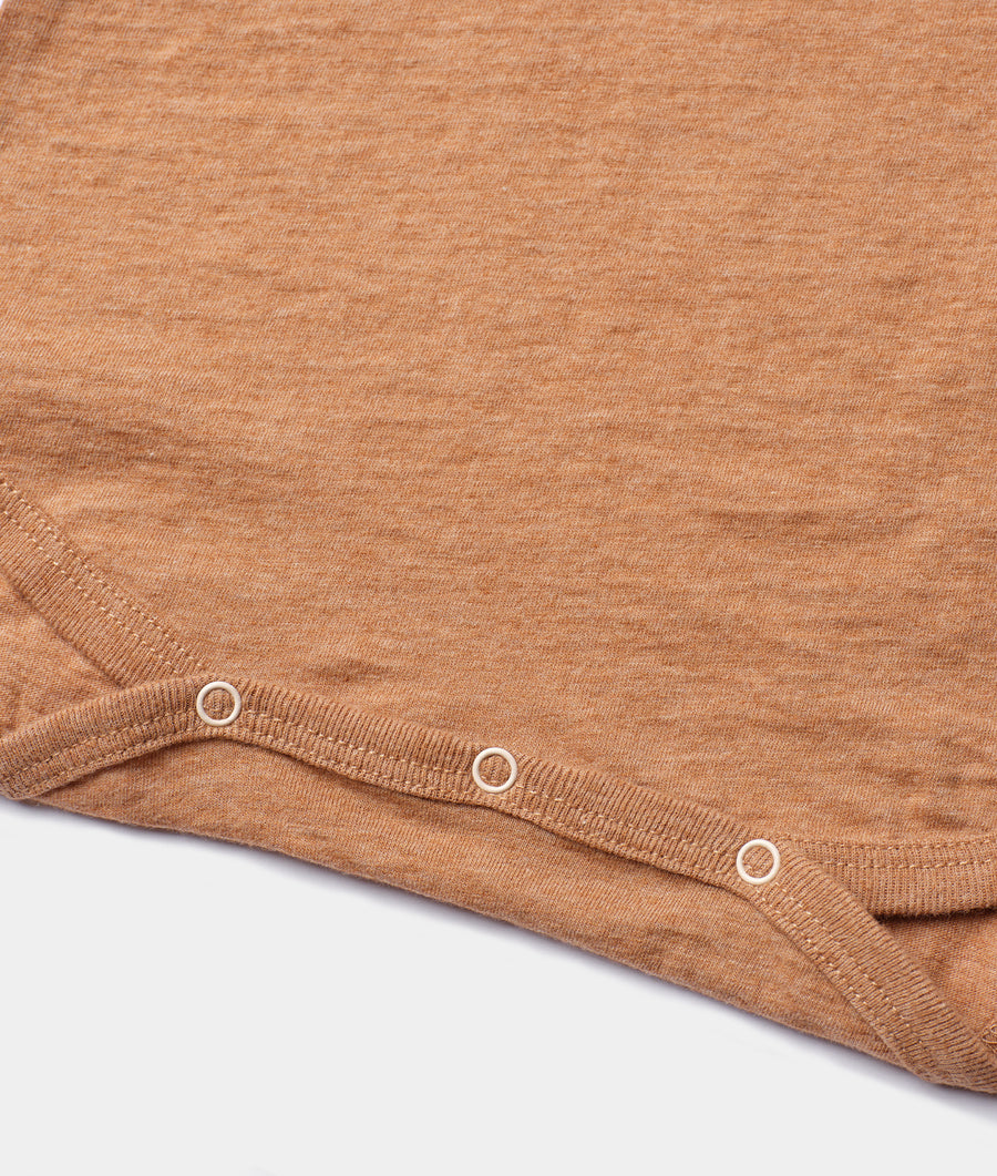 Closeup detail shot of a light brown organic cotton knit garment with eyelet trim accents - Industry of All Nations