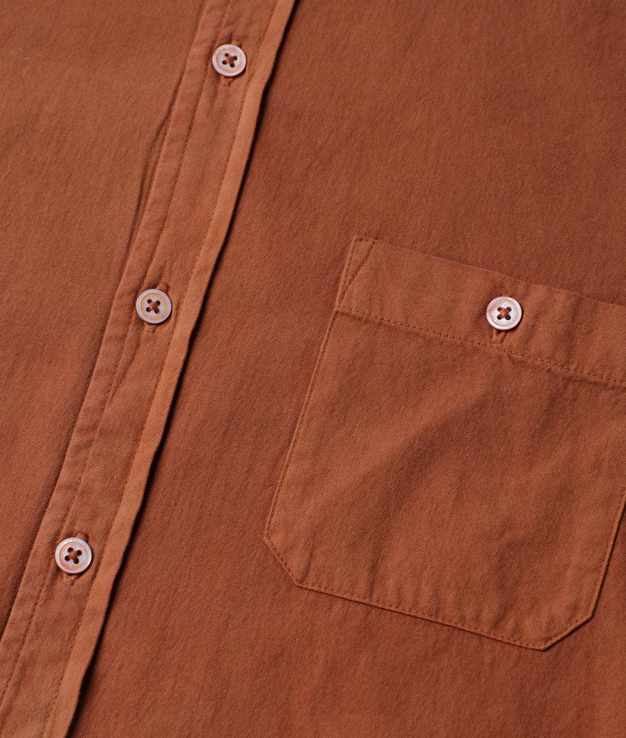 Detail shot of a rust-colored organic cotton button-down shirt with a chest pocket - Industry of All Nations