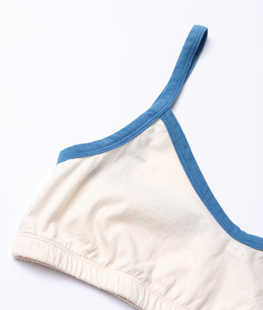 Cream and blue colored women's sports bra or crop top, displayed as a flat lay on a white background - Industry of All Nations
