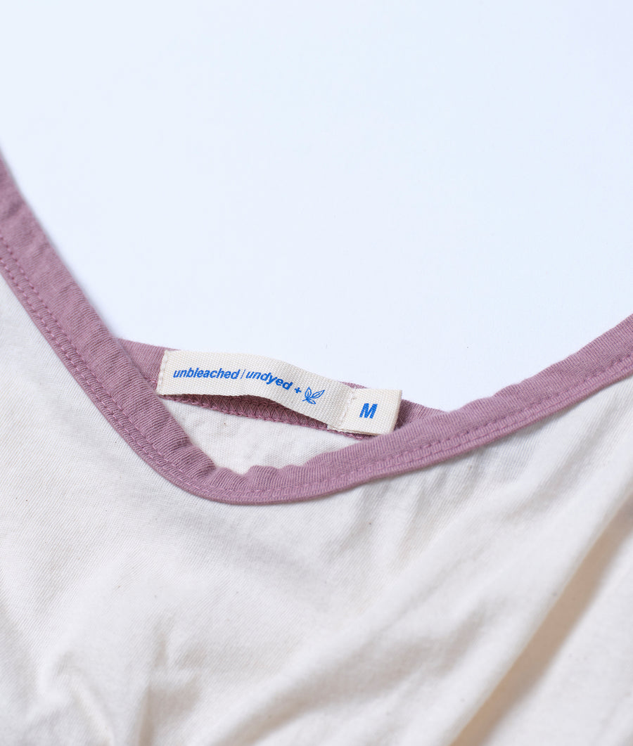 Detail shot of a light purple t-shirt with an 'unbleached | undyed' label on the collar - Industry of All Nations