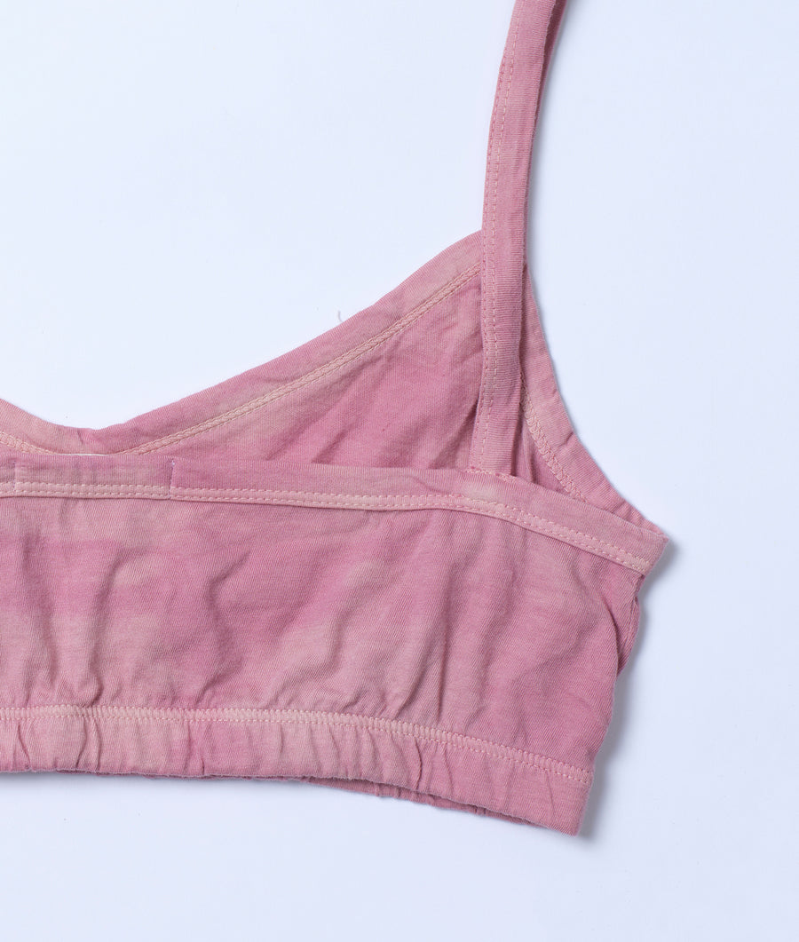 Detail shot of a pink sports bra or crop top with a scoop neckline and ruching in the front - Industry of All Nations