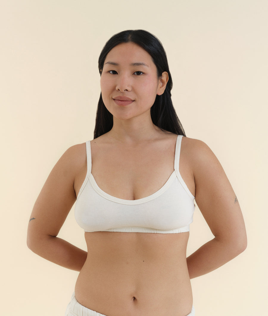 The image shows a woman wearing a white sports bra or crop top from Industry of All Nations.
