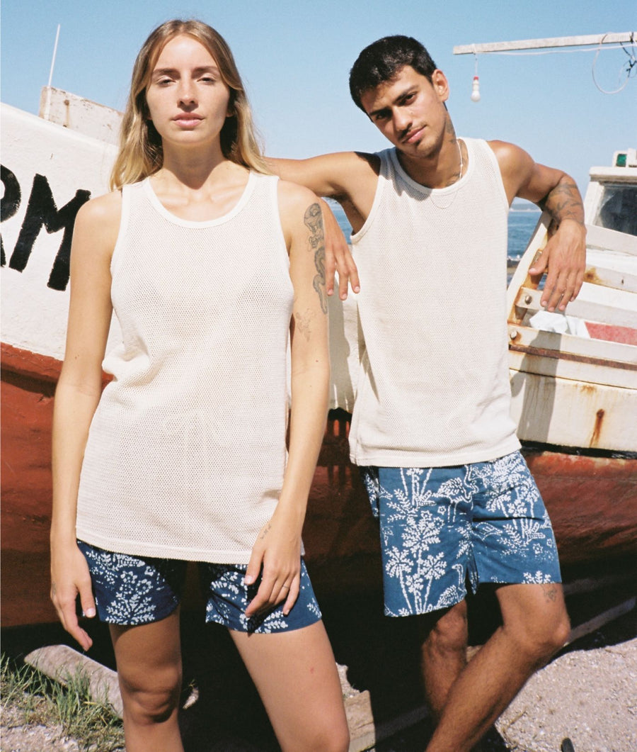 A man and a woman standing outdoors in front of a boat, wearing IOAN Batik Flamingo Boardshorts
