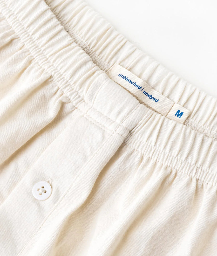 A close-up image of the elastic waistband and label on a white, pleated cotton pair of shorts - Industry of All Nations