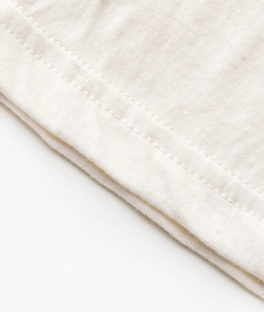 Beige organic cotton thermal underwear garment, folded and displayed against a plain background - Industry of All Nations