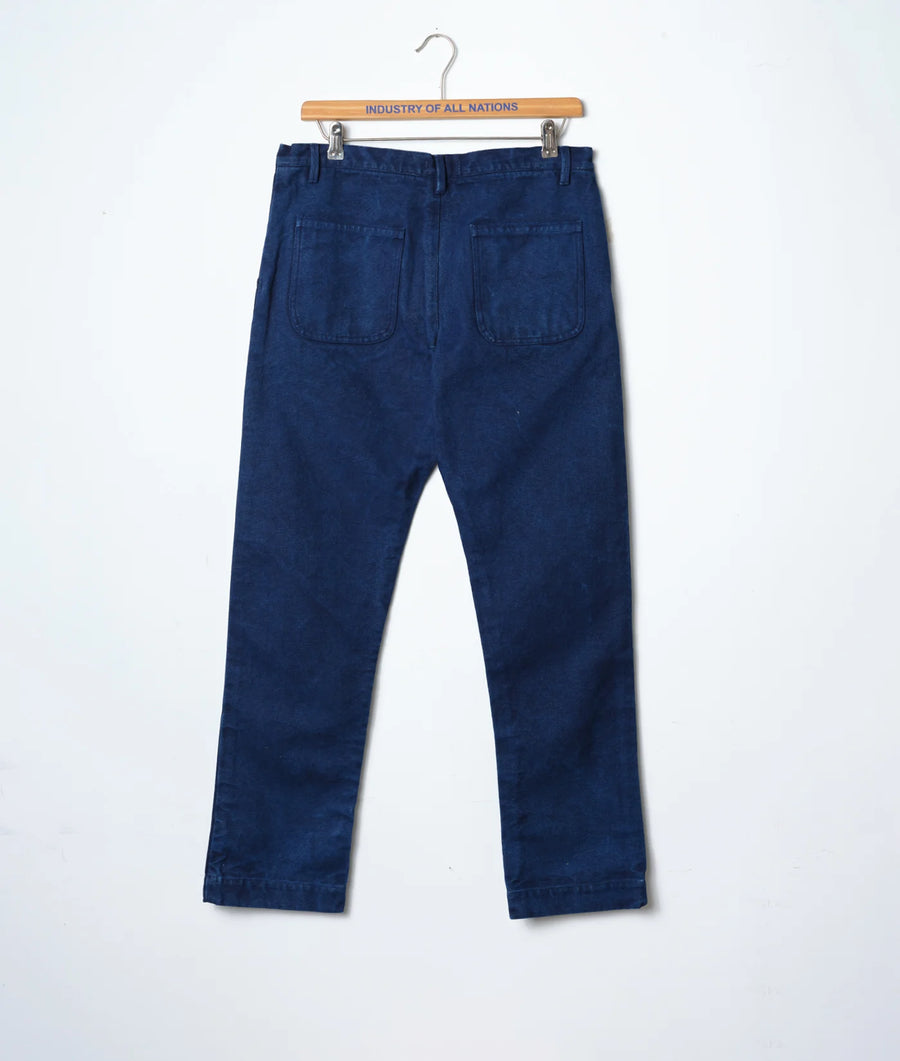 Navy blue denim work pants displayed on a wooden hanger with "Industry of All Nations" text - Industry of All Nations