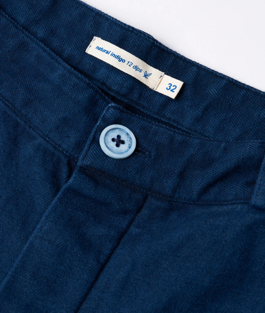 Close-up detail shot of a navy blue denim jeans with a size tag and button closure - Industry of All Nations
