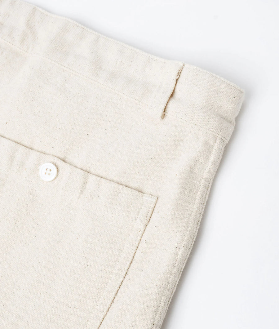 Detail shot of off-white organic cotton garment with button closure and visible stitching - Industry of All Nations