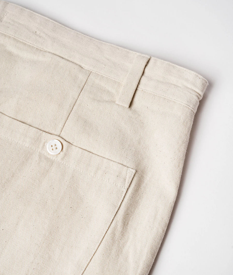 Flat lay detail shot of a pair of beige linen pants with a single button closure - Industry of All Nations