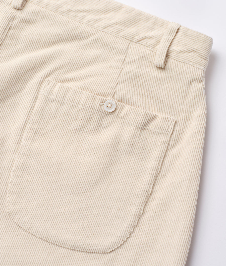 Detail shot of beige corduroy trousers with a single button and pocket - Industry of All Nations