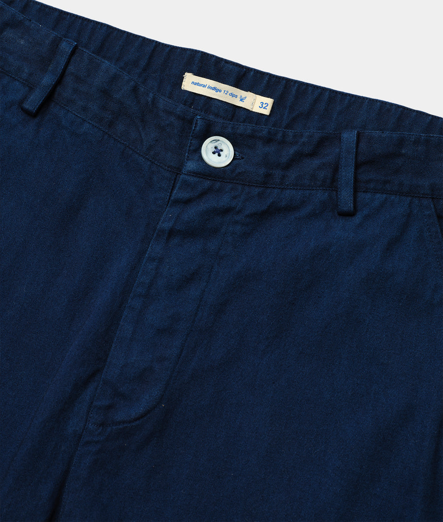 Close-up of navy blue cotton pants with white button and "Natural Indigo 12 oz" label - Industry of All Nations