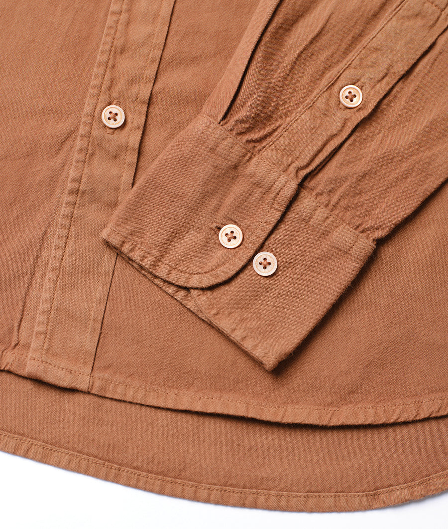 A close-up detail shot of a brown button-up shirt with four white buttons - Industry of All Nations