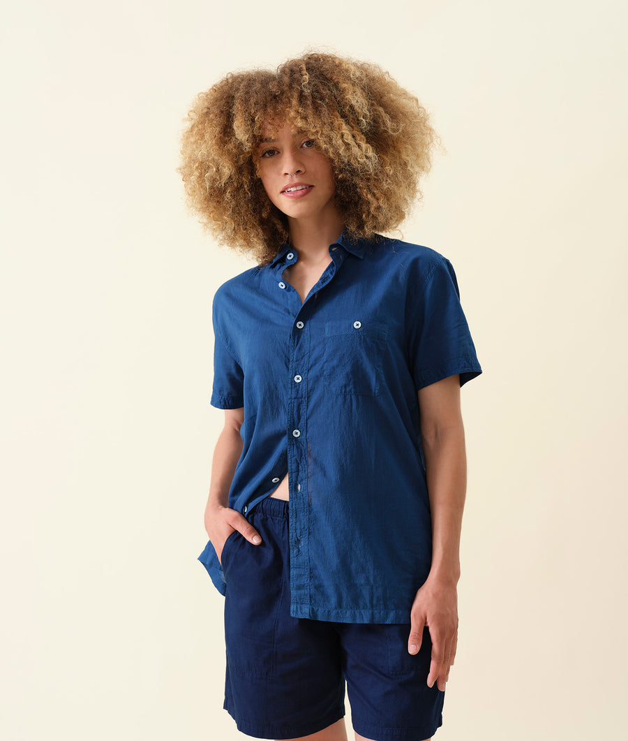 A young model wearing a navy blue linen button-up shirt with short sleeves - Industry of All Nations