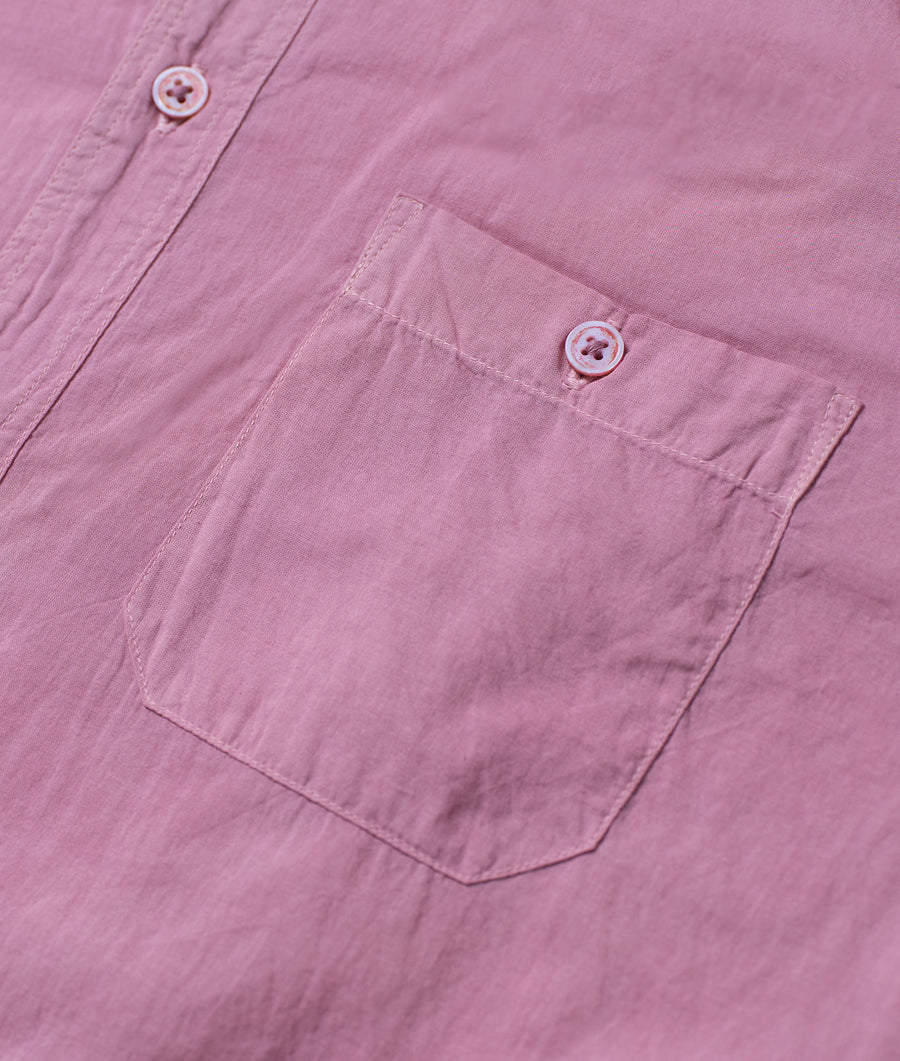 A close-up view of the front pocket and button details on a pink, button-up shirt by Industry of All Nations.