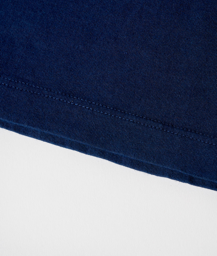 Close-up detail shot of a navy blue organic cotton tee with visible stitching along the neckline - Industry of All Nations