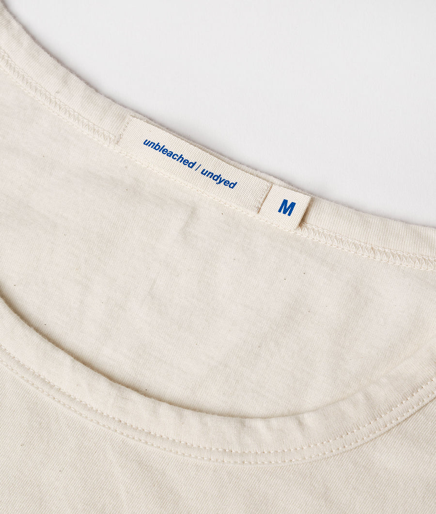 A close-up image of the neckline and size tag of a light-colored, plain cotton t-shirt, displayed flat - Industry of All Nations