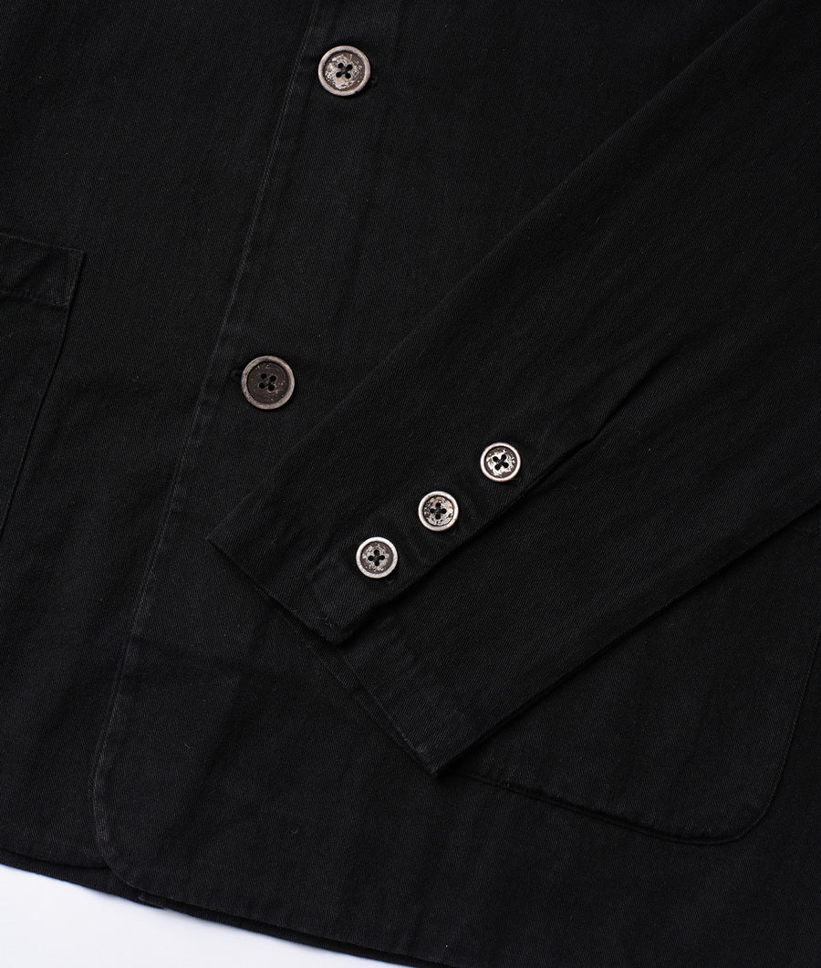 Detail shot of a black cotton jacket with four decorative white buttons - Industry of All Nations