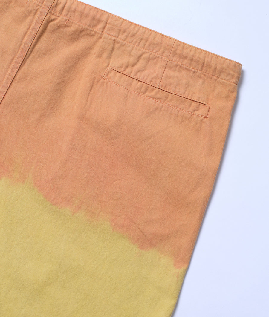 A detail shot of a pair of light brown trousers with yellow dye details, displayed on a flat surface - Industry of All Nations