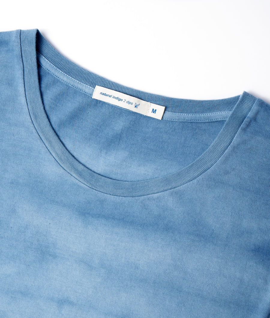 A close-up of a light blue, 100% cotton t-shirt with a natural indigo dye, displayed flat - Industry of All Nations