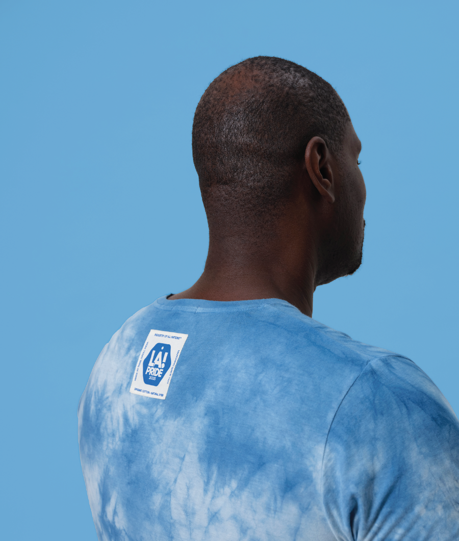 A man wearing a blue tie-dye t-shirt with the LA Pride logo on the back - Industry of All Nations
