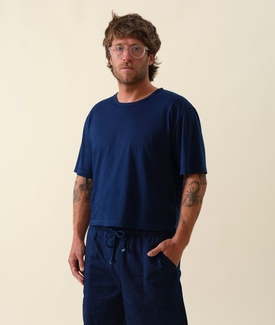 A male model wearing a navy blue organic cotton t-shirt and matching drawstring shorts, against a neutral background - Industry of All Nations