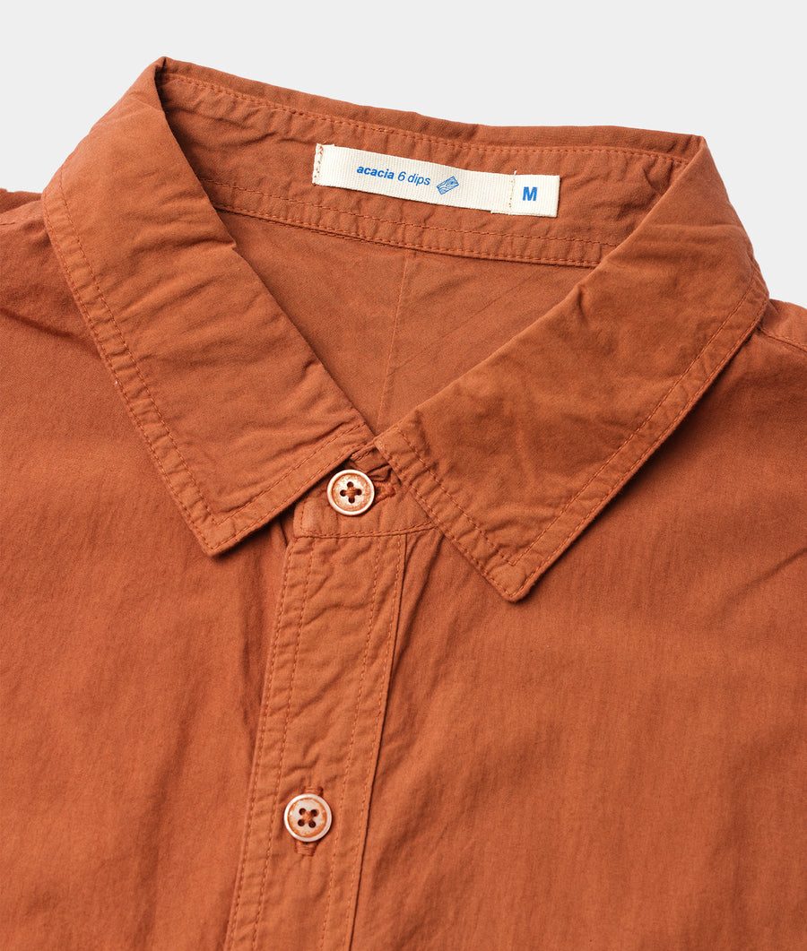 A close-up shot of a rust-colored cotton garment with button closure details - Industry of All Nations