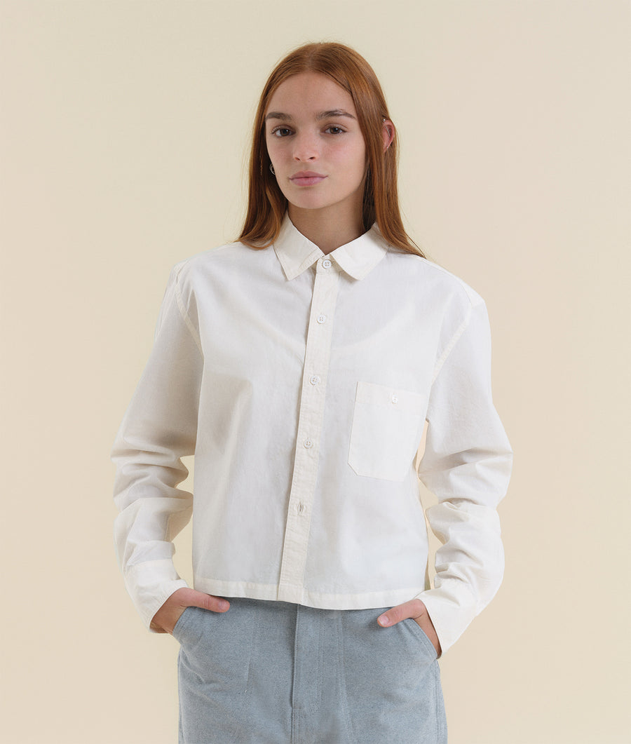Portrait of a young woman wearing a white cotton shirt from Industry of All Nations.